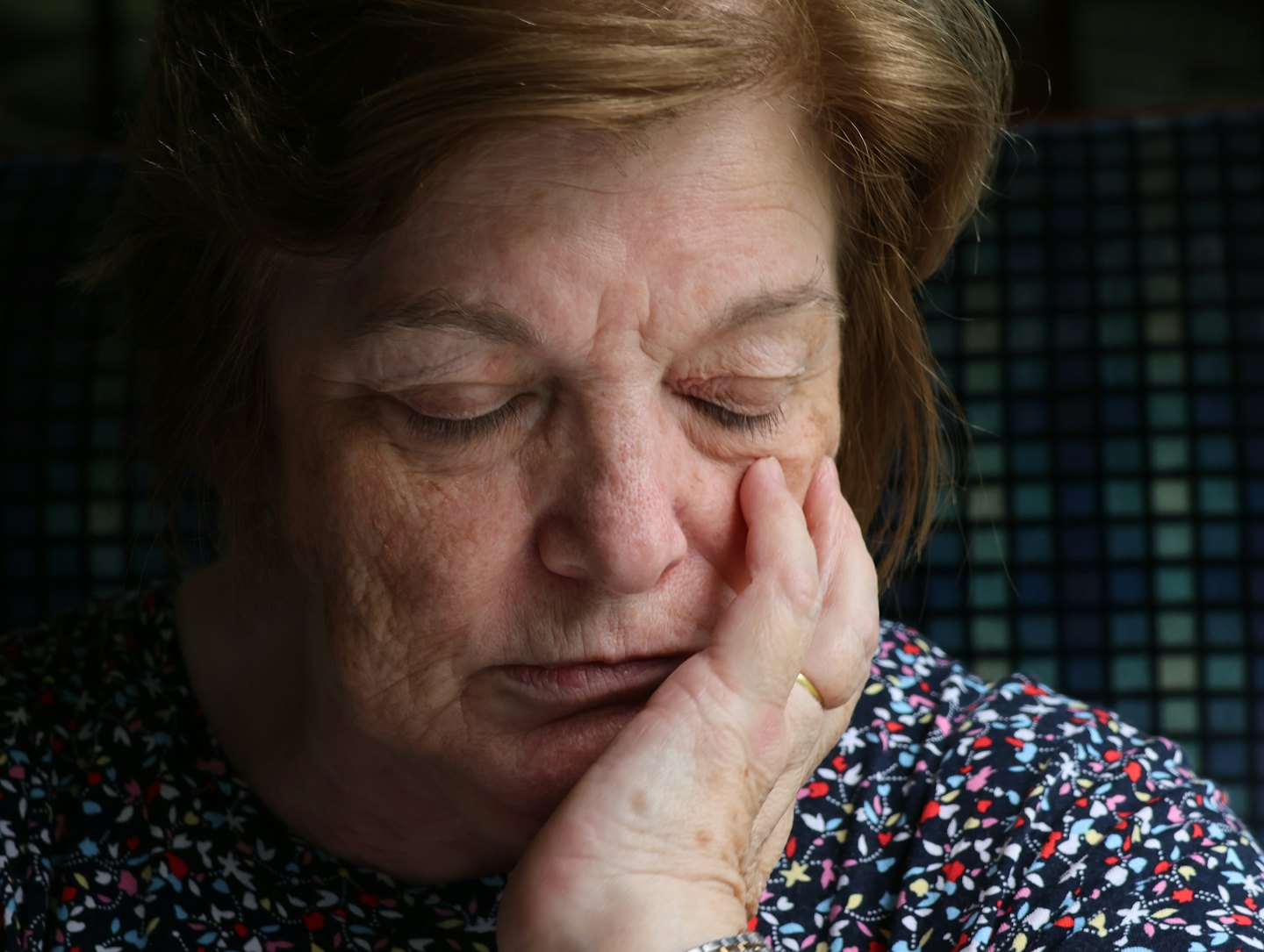 Žena seniorka si podopiera rukou bradu a má zatvorené oči.